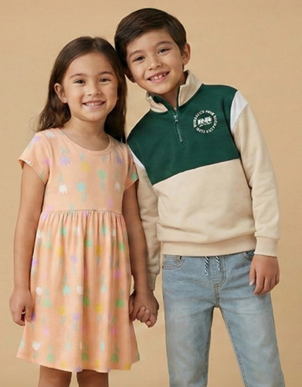 Ein junges Mädchen in einem pinken Kleid steht neben einem Jungen in einem schwarzen NFL-Hoodie vor einem leuchtend gelben Hintergrund.