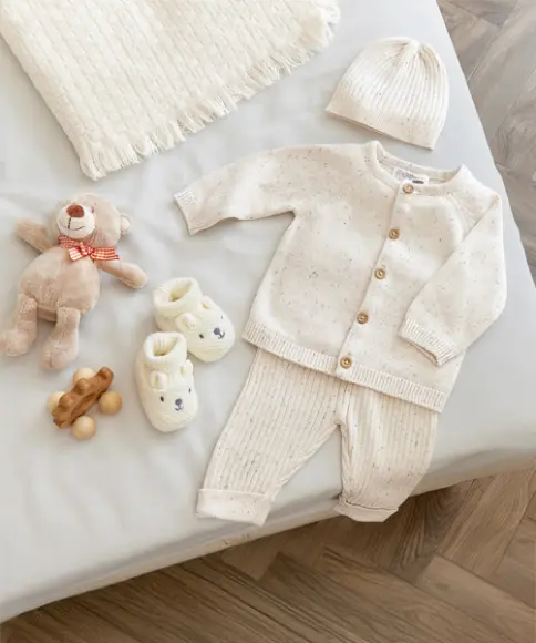 Ein Strickset für Babys liegt auf einer Matratze 