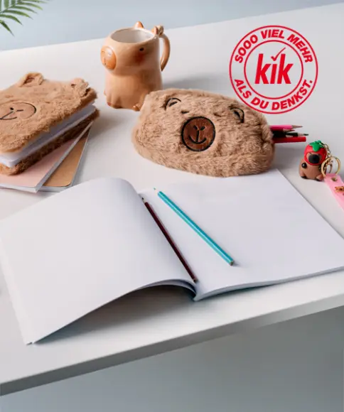 Eine gemütliche Schreibtischausstattung mit niedlichen Bären-Stifttaschen, einem leeren Notizbuch, bunten Stiften und einer verspielten Tasse mit Tiermotiv.
