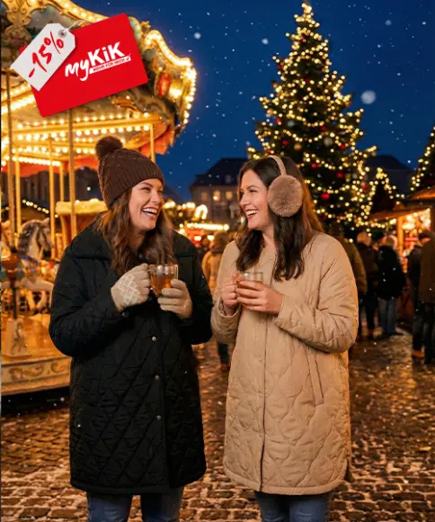 Ein gemütlicher Weihnachtsgeschenkkorb mit einem Plüschrentier, flauschigen Decken, einem Bärenbecher, heißer Schokoladenmischung und goldenen Ornamenten.