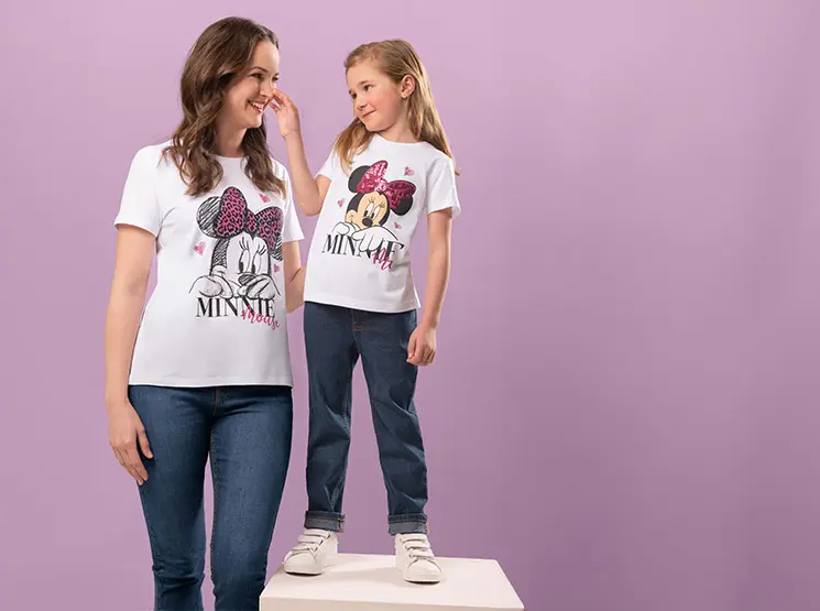 Eine Mutter und eine Tochter tragen eine Jeanshose und das gleiche Minnie Maus T-Shirt