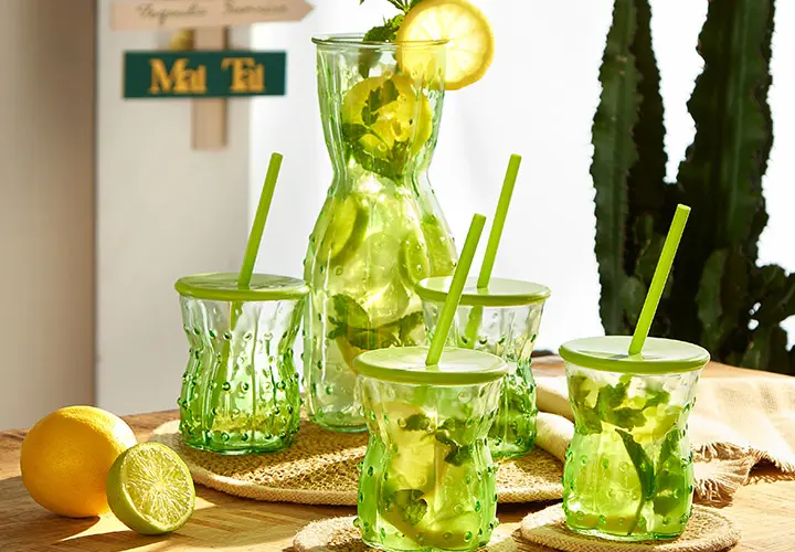 Ein 4er Glas-Set in grün mit Decken und Strohhalm, dazu passen eine Karaffe