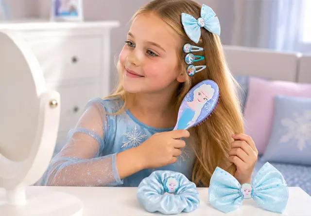 Mädchen bürstet ihre Haare mit Disney Die Eiskönigin Haaraccessoires vor dem Spiegel – verspielte Styling-Accessoires für Kinder