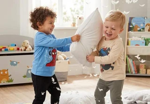 Spider-Man Nachtwäsche für kleine Superhelden Zwei Kinder in Spider-Man Schlafbekleidung liefern sich eine fröhliche Kissenschlacht im Kinderzimmer – bequeme Nachtwäsche für kleine Superhelden-Fans