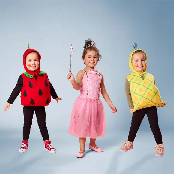 Drei Kinder in lustigen Obstkostümen: Erdbeere, Ananas und eine Prinzessin in einem rosa Kleid