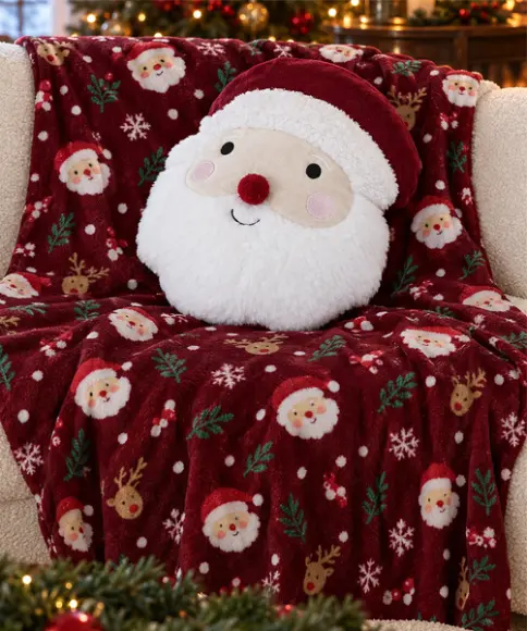 Kuschelige rote Weihnachtsdecke mit Weihnachtsmann- und Rentiermotiven sowie rundem Weihnachtsmann-Kissen auf einem Sofa