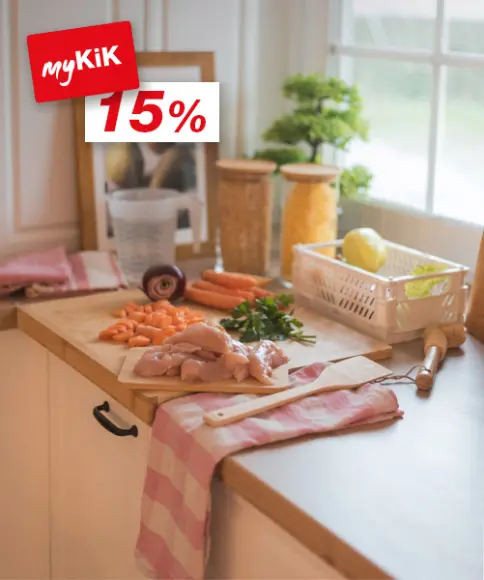 Eine helle Küchentheke mit Hähnchenbrust, gehackten Karotten, Kräutern und einer Vielzahl von Zutaten in Gläsern, bereit zum Kochen.