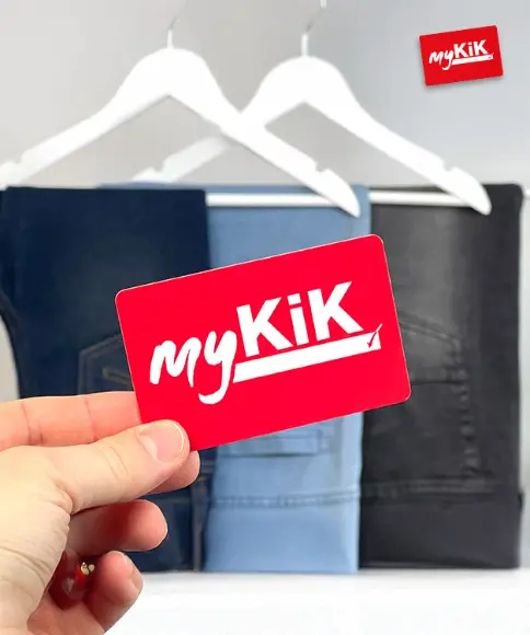 Eine Hand hält eine rote myKiK-Kundenkarte vor einer hängenden Jeans in verschiedenen Farbtönen.