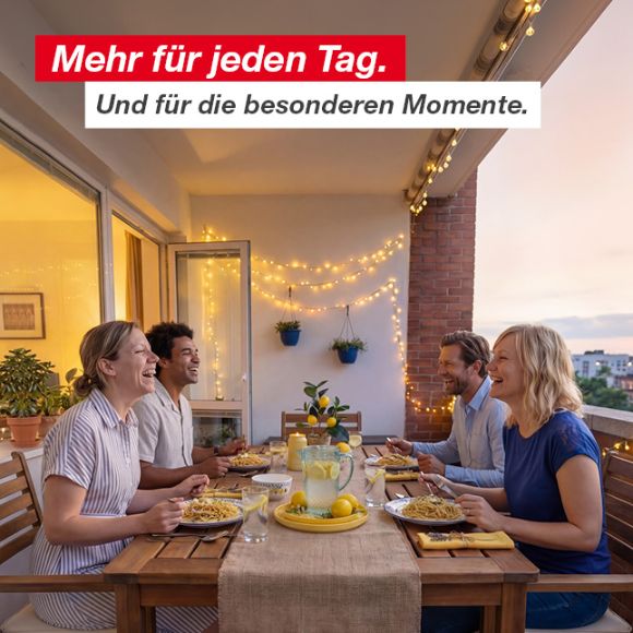 Vier Personen genießen am Abend eine Mahlzeit mit Pasta und Zitronenlimonade auf einem dekorierten Balkon mit Lichterketten und Topfpflanzen.