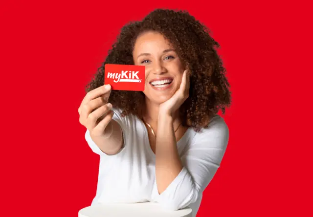 Eine Frau hält die myKiK-Vorteilskarte lächend in die Kamera