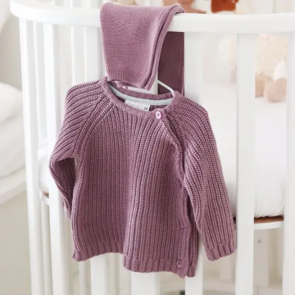Ein Baby-Sweater hängt an einem Kleiderständer.