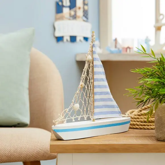 Ein dekoratives Modellsegelboot mit gestreiftem Segel steht auf einem Holztisch