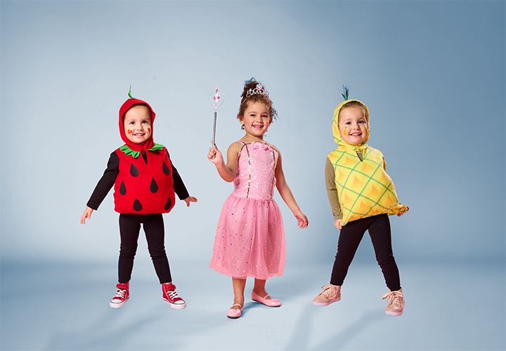 Drei Kinder in lustigen Obstkostümen: Erdbeere, Ananas und eine Prinzessin in einem rosa Kleid