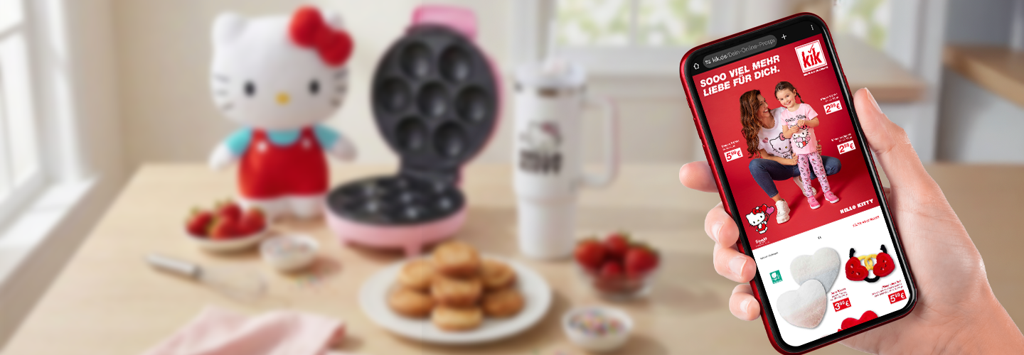 Hand hält Smartphone mit Hello Kitty Werbung, pinkes Waffeleisen und Snacks auf dem Tisch