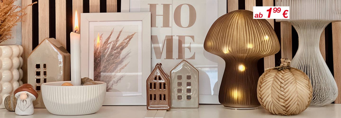 Eine gemütliche Ausstellung von Dekorationsartikeln wie Kerzen, Keramikhäusern und stilvollen Lampen vor einem Holzhintergrund, wobei die Preise hervorgehoben sind.