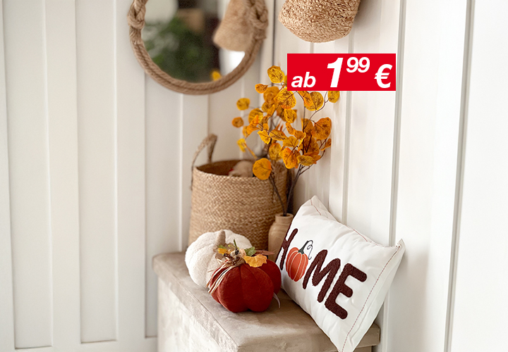 Gemütliche Wohnkultur mit einem runden Spiegel, geflochtenen Körben, Herbstblättern und einem dekorativen Kissen mit der Aufschrift „HOME“ und einem Kürbis-Akzent.