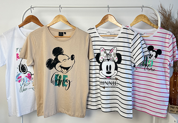 Ein Kleiderständer mit vier verspielten Mickey- und Minnie-Mouse-T-Shirts in verschiedenen Farben und Designs.