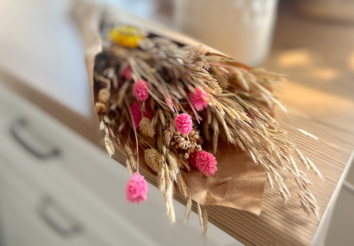 Auf einer Theke befindet sich ein Bouquet aus getrockneten Blumen.